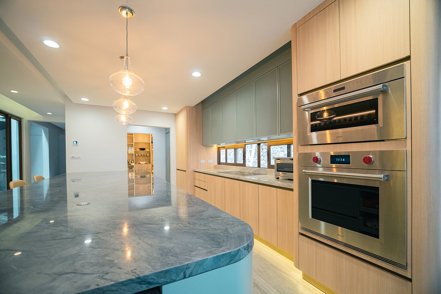 Custom modern kitchen designed by Mobilinea in Costa Rica with wood cabinetry and green island